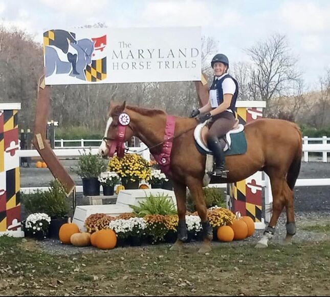 Michelle riding Delvin in front of the Maryland Horse Trials banner
