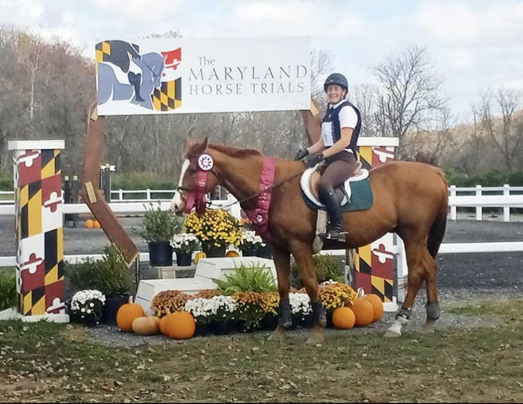 Michelle riding Delvin in front of the Maryland Horse Trials banner